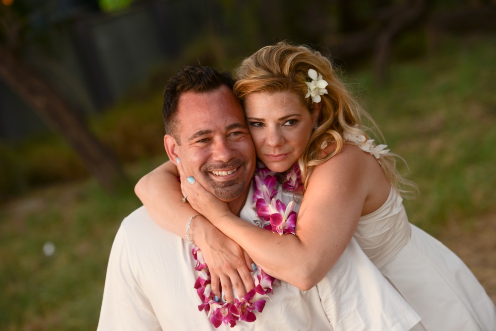 Man and Woman Dressed in White with Hawaiian Leis Celebrating Vow Renewal in Paradise