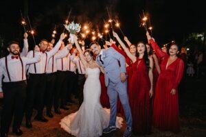 Destination wedding guests simulate a wedding ceremony tradition called arch of swords forming a tunnel with sparklers and upstretched arms for a couple's exit